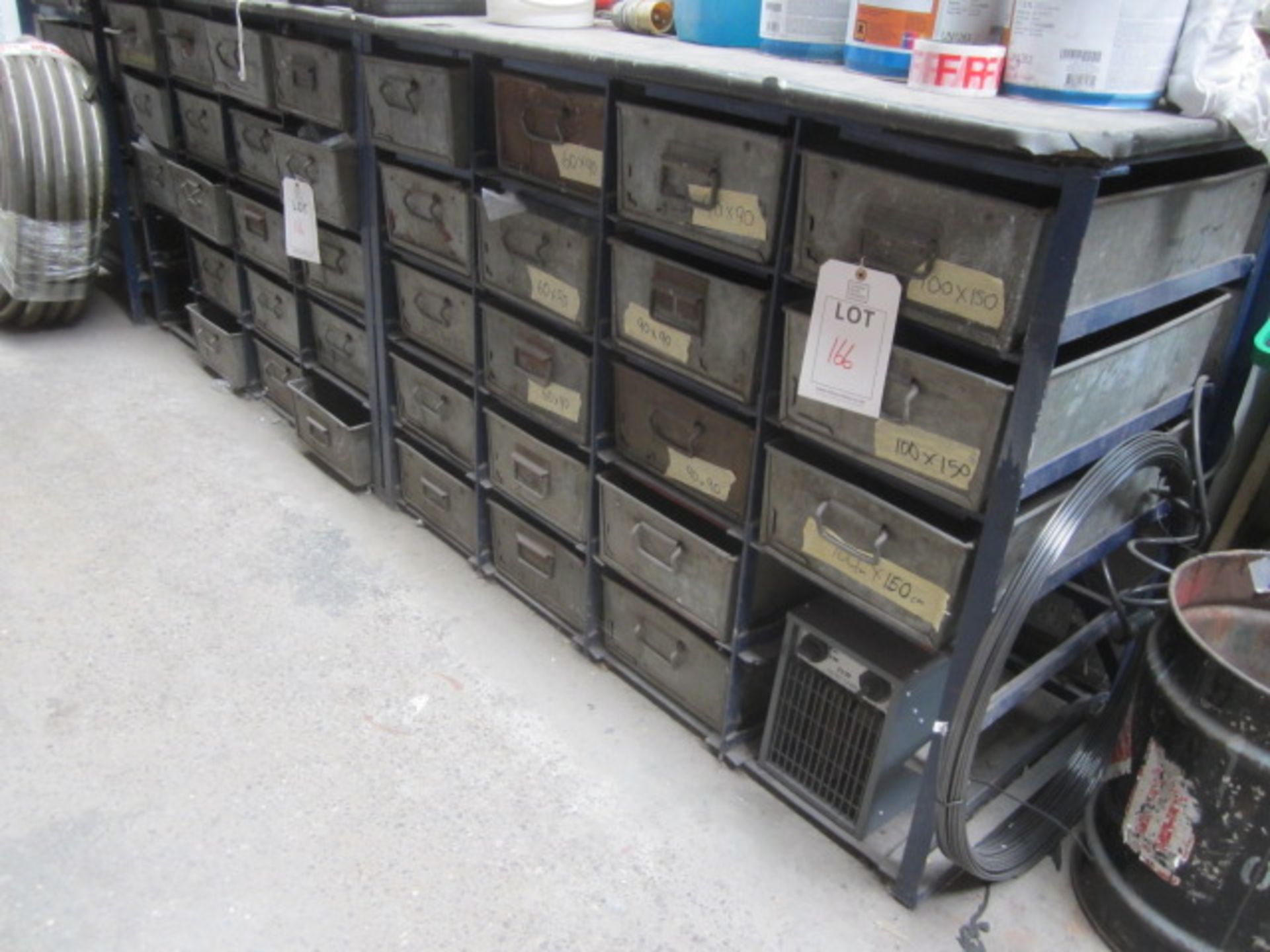 Three 20 bin steel storage racks and assorted stock contents including metal sample plates,
