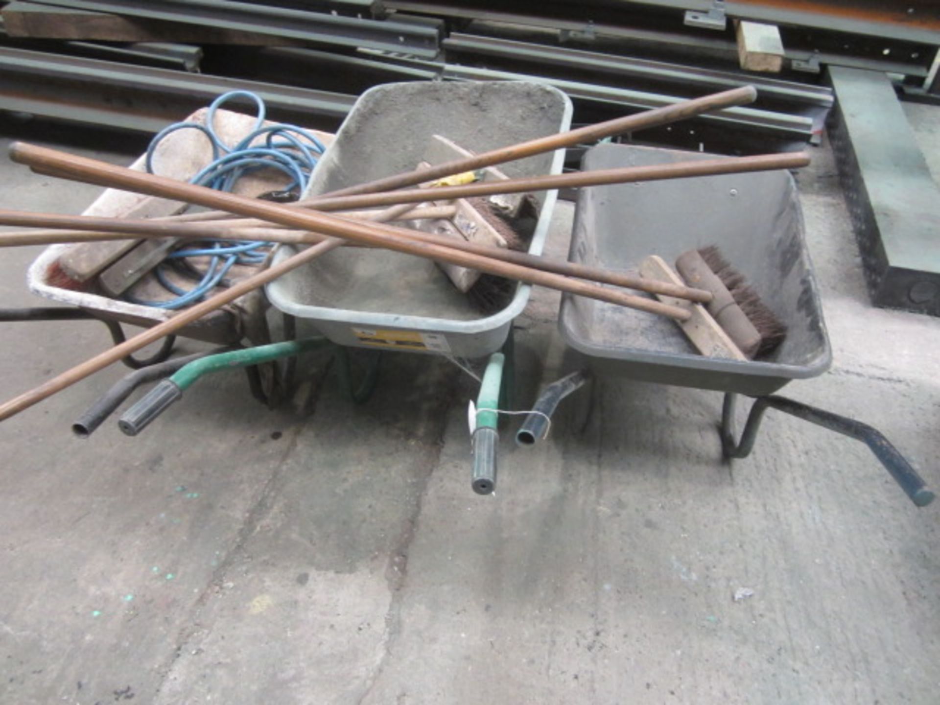 Three wheelbarrows and assorted yard brushes