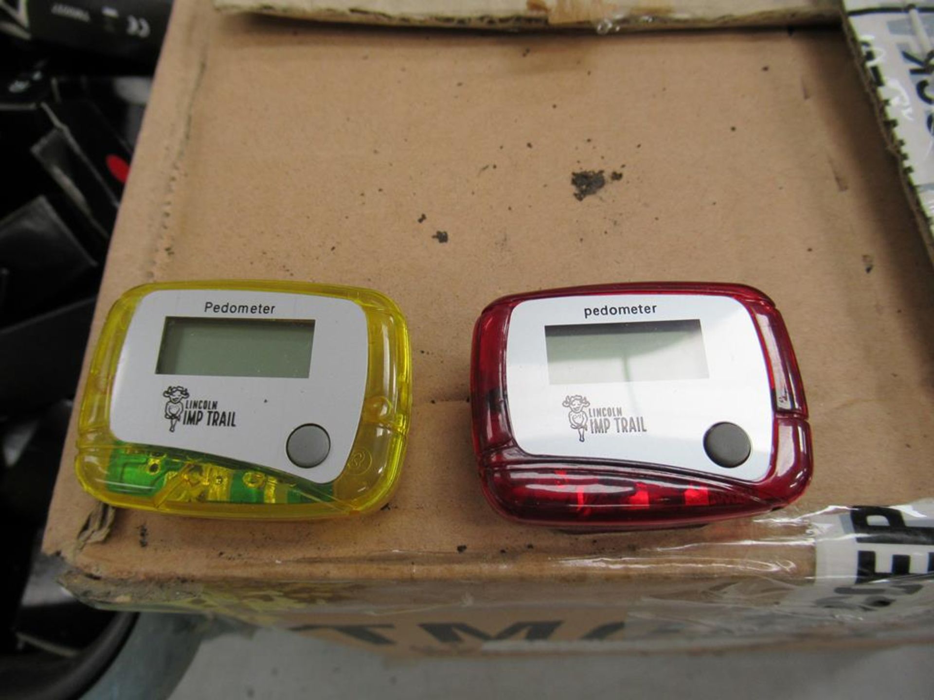 Large qty of red and yellow Lincoln Imp pedometers to plastic crate and box