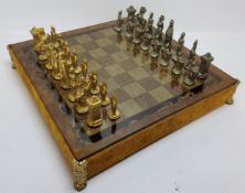 A cast metal chess set the glass playing board suspended on cast corner legs over the sectioned