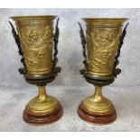 A pair of country house gilt bronze pedestal urns, decorated in relief with flora and fauna