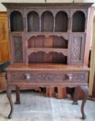 A late Victorian English oak dresser, profusely carved throughout, the oversailing leaf carved
