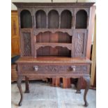 A late Victorian English oak dresser, profusely carved throughout, the oversailing leaf carved