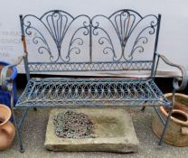 A wrought iron garden bench, scrolling decoration throughout