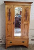 An Art Nouveau satin wood single wardrobe with oversized Art Nouveau copper escutcheons raised on