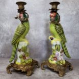 An impressive pair of large gilt metal mounted porcelain parrot candlesticks, each modelled as a