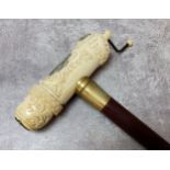 An unusual 'scrimshaw' walking stick carved with whaling ship, compass and fish, hardwood shaft, the