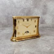 A Jean Roulet Le Locle brass desk quartz clock, cream face, gold Roman numerals & hands, moonphase