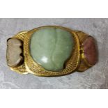 A Chinese gilt metal belt buckle set with a shaped central jade stone,