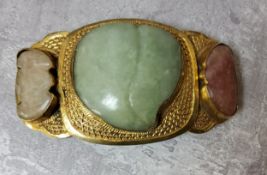 A Chinese gilt metal belt buckle set with a shaped central jade stone,