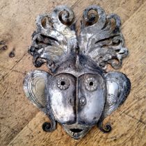 An Indian silver plated metal wall mask of a deity with peacock headdress 31 x 26cms