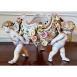 A Meissen centre piece the pierced bowl decorated with applied roses supported by three Putti base ,