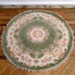 A circular rug, in tones of apple green and a soft pink, 155cm diameter.