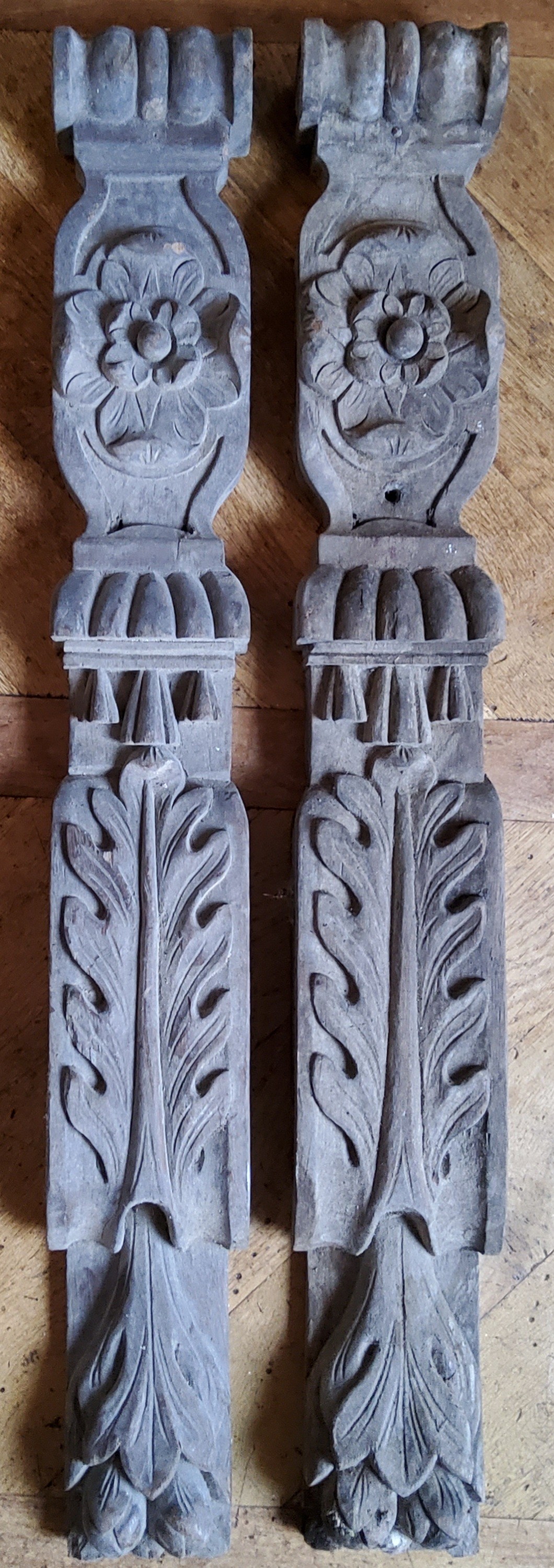 A pair of early 19th century carved oak mantel legs, decorated with a Tudor Rose, stylised oak