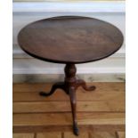A George III flamed mahogany one piece tilt top circular occasional table, raised on a boldly turned