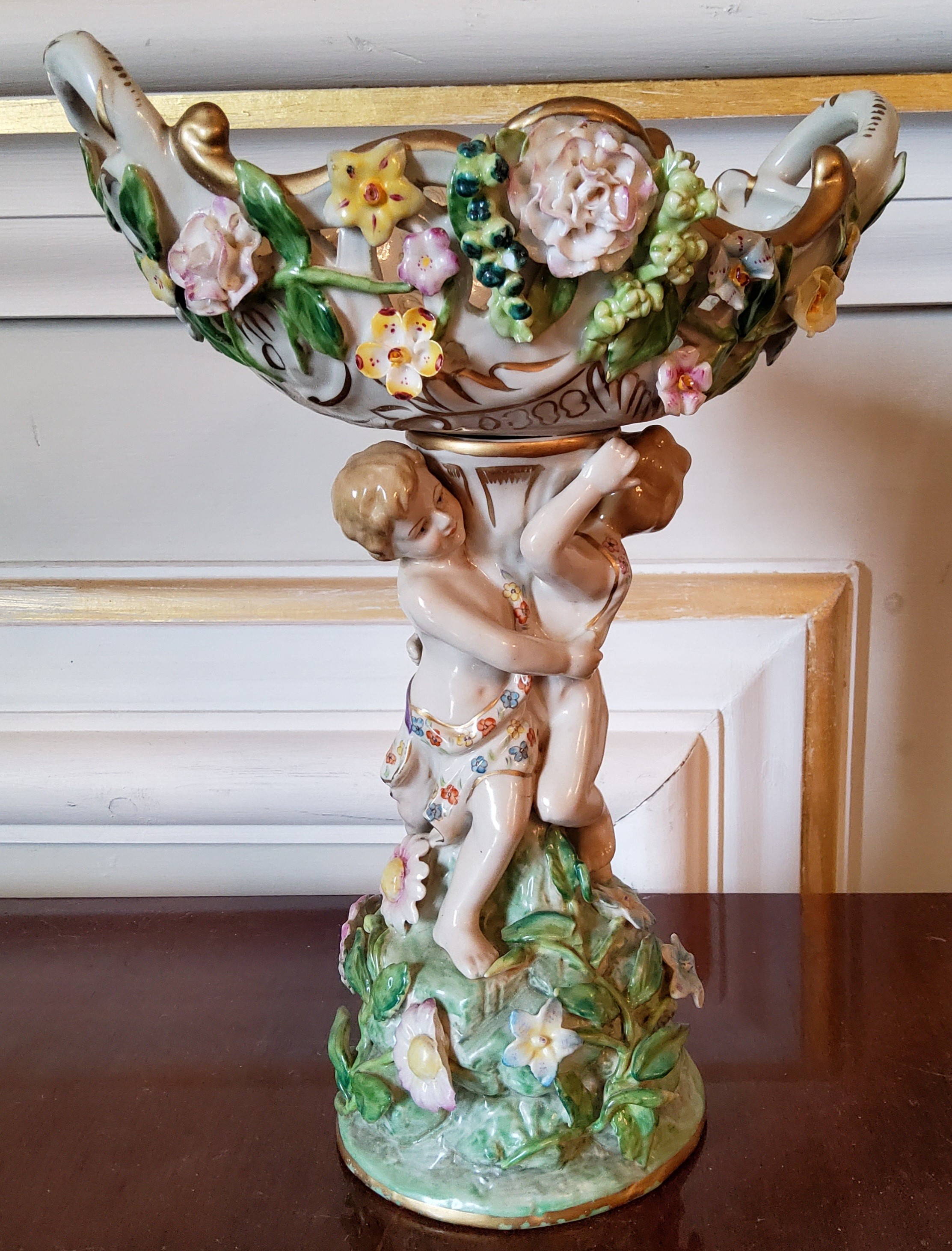 A Meissen centre piece with entwined putti supporting a central pierced bowl with applied flowers,