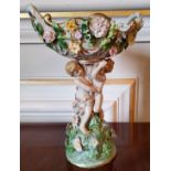 A Meissen centre piece with entwined putti supporting a central pierced bowl with applied flowers,