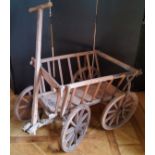 A rustic farmhouse pine dog cart, with steel rimmed wooden spoked wheels and articulated steering