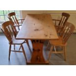 A farmhouse pine kitchen table with four chairs including two carvers, the table support with