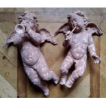 A pair of wall hanging plaster putti playing trumpets, terracotta effect (one missing trumpet)