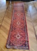 A large hand knotted Hamadan runner with five elephant foot gourds, in tones of red and blue 487cm x