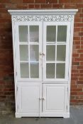 A modern hall cupboard painted white with oversailing ogee cornice above a pierced ivy leaf panelled