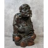 A Chinese carved rosewood immortal holding a mythical fish 28cms h