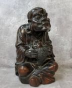 A Chinese carved rosewood immortal holding a mythical fish 28cms h