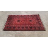 An Afghan rug in tones of maroon and black