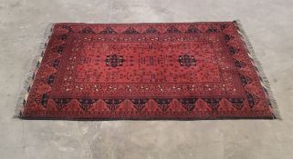 An Afghan rug in tones of maroon and black