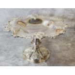 A silver-plated shaped pedestal dish embossed in relief decoration 19cms high