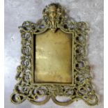 An early 19th century French brass easel back picture frame decorated in relief with putti cartouche