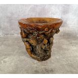 A Chinese 'rhinoceros horn' libation cup carved with immortals beneath a flowering prunus tree on