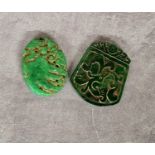 Two Chinese jade amulet pendants, the oval amulet carved with monkeys on a rocky outcrop, yhe larger