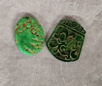 Two Chinese jade amulet pendants, the oval amulet carved with monkeys on a rocky outcrop, yhe larger