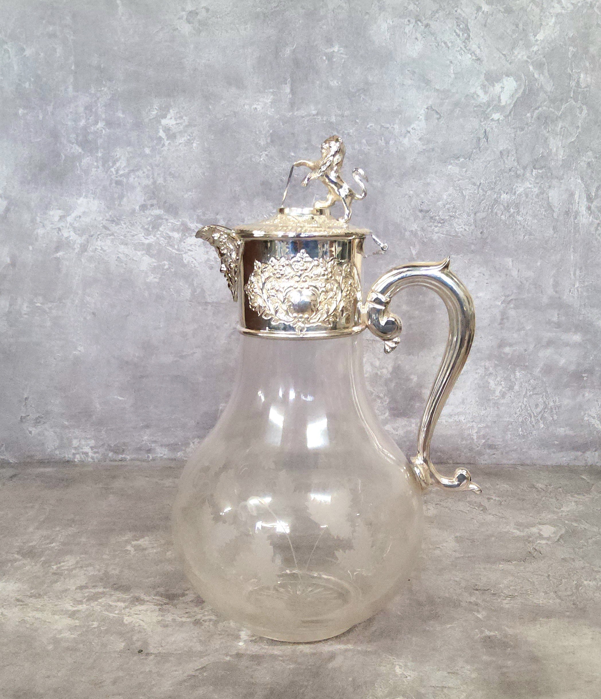 An elegant silver plate mounted claret jug, terminating with a lion and shield hinged lid with green