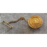 Mining interest - a scarce 9ct gold lapel badge with chain & safety chain, embossed in relief with a