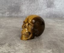 A carved tiger's eye gemstone skull 6.5cms