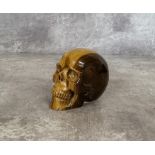 A carved tiger's eye gemstone skull 6.5cms