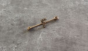 A rose gold coloured bar brooch in form of a safety pin mounted with a letter F set with seed pearls