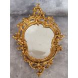 A small gilt bronze cartouche shaped looking glass with bevelled and slightly foxed mirror plate