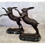 A pair of bronze fighting hares on marble plinth bases 30cms high