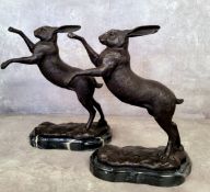 A pair of bronze fighting hares on marble plinth bases 30cms high