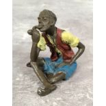 A Bergman style cold painted bronze of a young African man smoking a pipe, stamped GESCHUTZT 8127 to