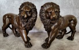 A pair of bronze lions 33cms x 24cms high