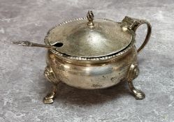 A Harrods silver mustard pot hinged cover, pad feet, scroll handle, Bristol Blue liner, hallmarked