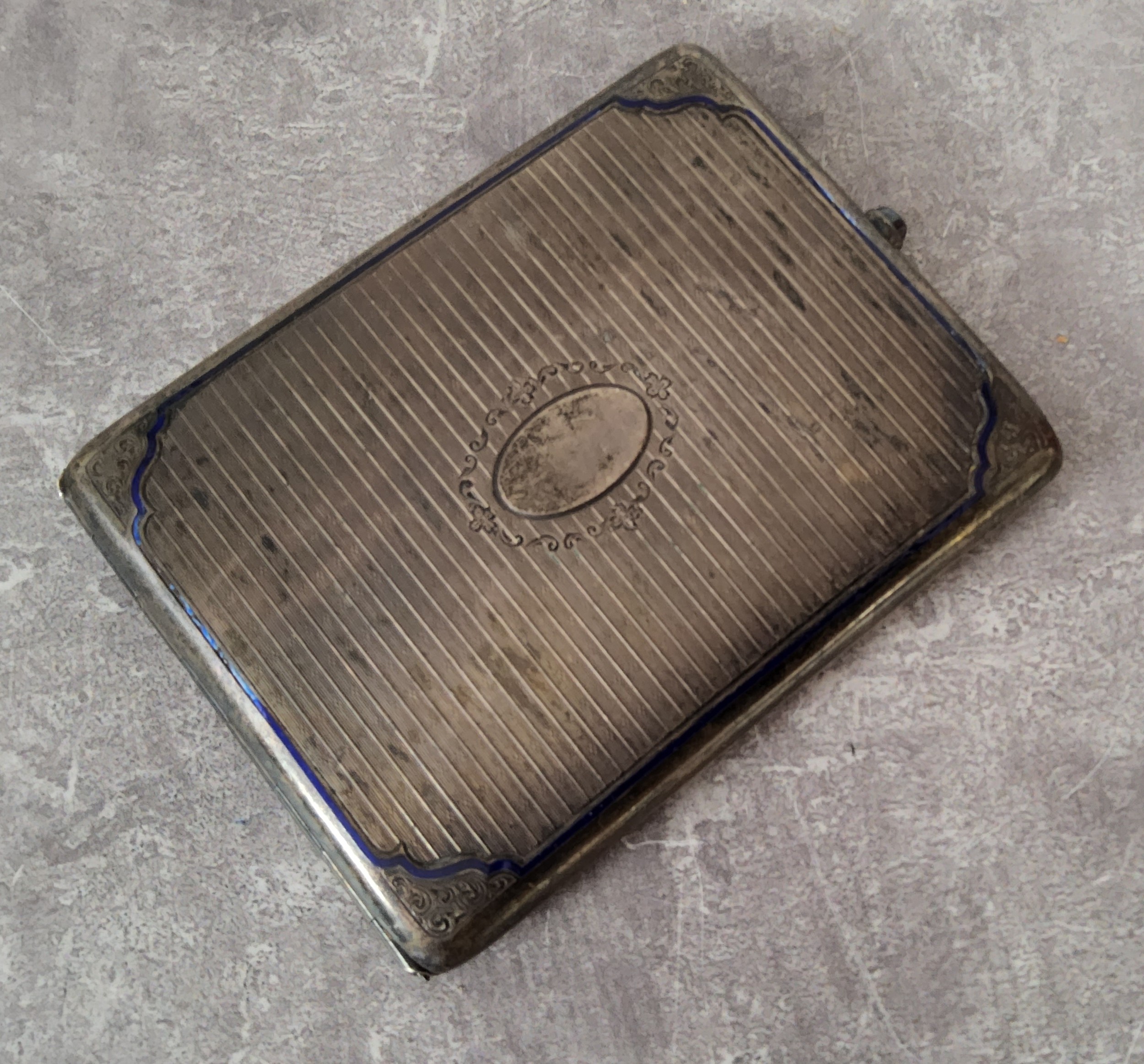 A continental silver cigarette case engraved & chased decoration, scroll spandrels blue enamel