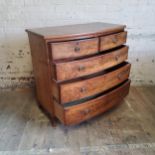 A George III walnut bow front chest of drawers of two short above three long drawers c.1800