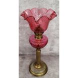 A 19th century French cranberry glass and brass table oil lamp by Gaudard, with wavy ribbed shade