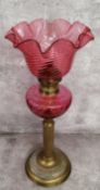 A 19th century French cranberry glass and brass table oil lamp by Gaudard, with wavy ribbed shade